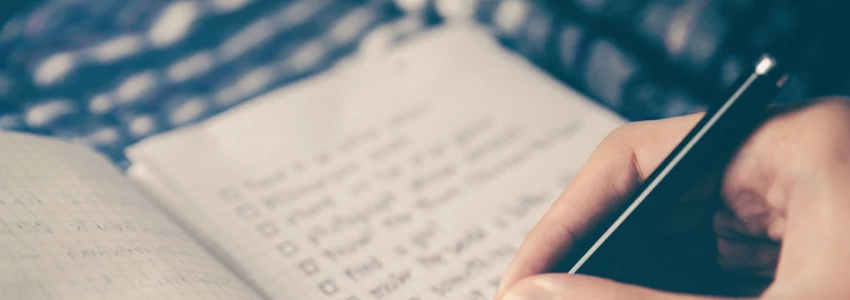 Person writing a check list in a notebook